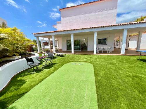 阿德耶Beautiful Villa Amorio - Private Heated Pool with Sea Views & WIFI的一个带绿地的庭院,草坪上摆放着椅子,房子里还摆放着