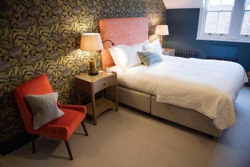 奇切斯特Purchases Restaurant & Accommodation的一间卧室配有一张床和一张红色椅子