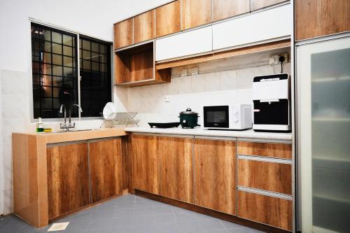 万挠Peach Homestay Tasik Puteri的厨房配有木制橱柜、水槽和微波炉