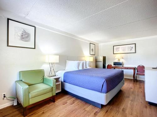 杰克逊维尔Stayable Jacksonville North的配有一张床和一把椅子的酒店客房