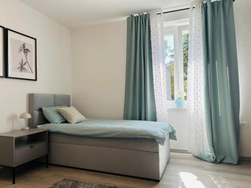 波尔托罗Luxury apartment magical Portorose的一间卧室配有一张带蓝色窗帘的床和一扇窗户