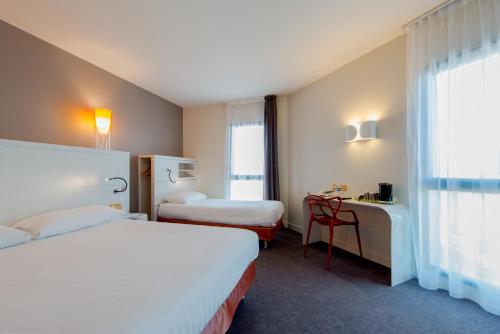 拉罗谢尔罗歇尔中心齐亚迪酒店 - 莱斯米尼蒙的酒店客房配有两张床和一张书桌