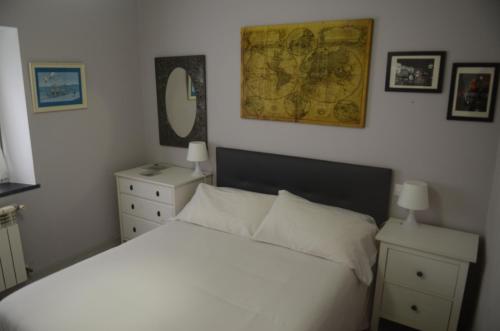 卢阿尔卡La Casina de Luarca的卧室配有白色的床和墙上的地图