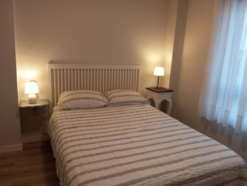擞莫apartamento Somo的一间卧室配有一张大床和两盏灯