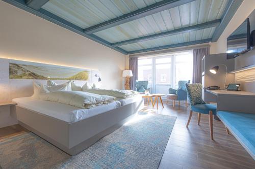 诺尔多夫阿特鲁姆希尔布里克基努斯温泉度假酒店的卧室配有一张白色大床和一张书桌