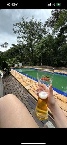 瓜拉图巴Sitio Bonanza的游泳池旁喝杯啤酒的人