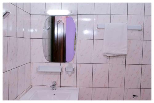 BafoussamRésidences K and D CAMOCO的白色瓷砖浴室设有镜子和水槽