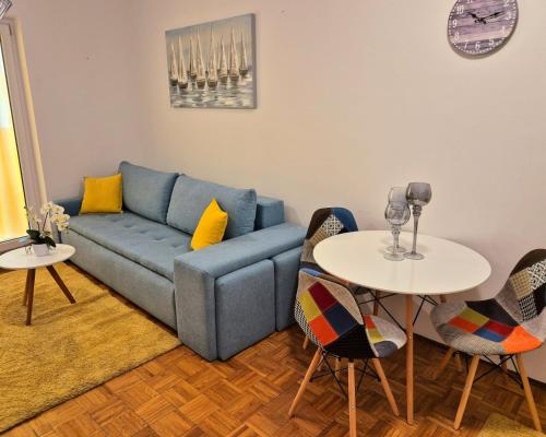 塞尔瑟Apartman Lopar Selce的客厅配有蓝色的沙发和2张桌子