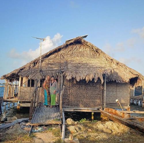 WichubualáPrivate Traditional Hut on the water with 2 rooms的两个人站在茅草屋前