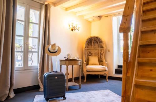 圣雷米普罗旺斯Hôtel Gounod的一间房间,配有手提箱、椅子和窗户