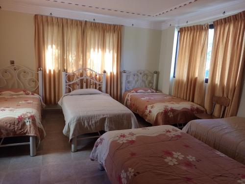 TorotoroHoSTAL SANTA BARBARA的酒店客房,设有三张床和窗帘