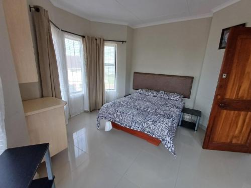 乌旺戈海滩3 Queensway Uvongo的一间卧室配有一张带被子的床和两个窗户