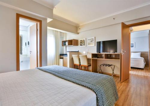 里贝朗普雷托Matiz Vilaboim Ribeirão Preto的配有一张床和一张书桌的酒店客房