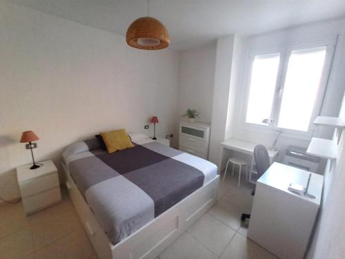 巴哈马尔Apartamento Bajamar Tenerife的一间卧室配有一张床、一张书桌和两个窗户。