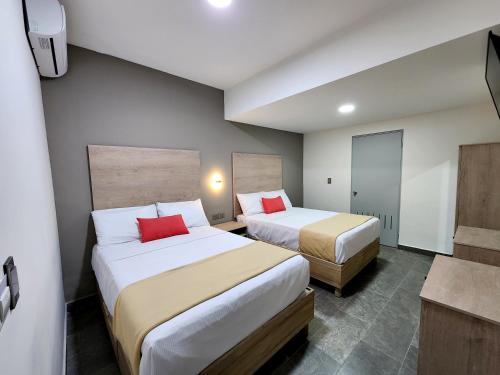 托雷翁Hotel Roque的两张位于酒店客房的床铺,配有红色枕头