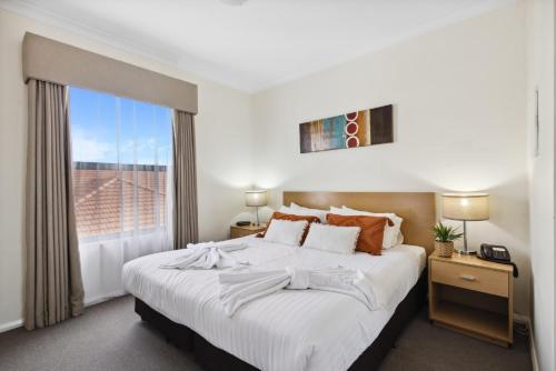 珀斯Urban Apt in the Heart of Northbridge的卧室设有一张白色大床和一扇窗户。