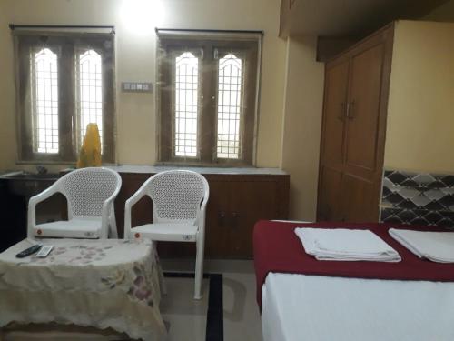 巴德拉恰拉姆Kodali Homestays的一间客房配有两张床、一张桌子和两把椅子