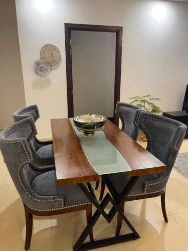 伊斯兰堡1 Bedroom Furnished Apartment at Eighteen Islamabad的餐桌,配有黑色椅子和碗