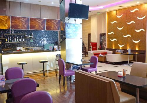 雅加达World Hotel Jakarta - Bandengan的一间设有紫色椅子的餐厅和一间酒吧