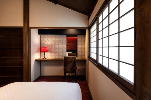 京都Rinn Shijo Machiya的一间卧室配有一张床、一张书桌和一个窗户。