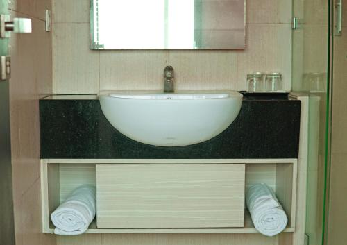 雅加达World Hotel Jakarta - Bandengan的浴室配有盥洗盆和带毛巾的台面。