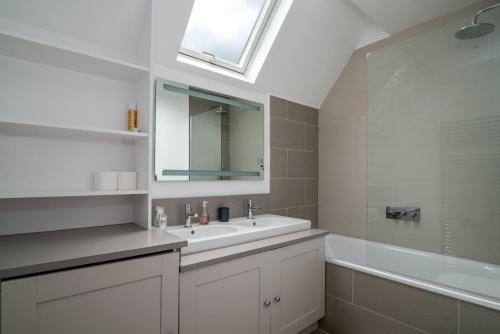 伦敦GuestReady - Chic in the heart of Kensington的浴室配有盥洗盆、镜子和浴缸