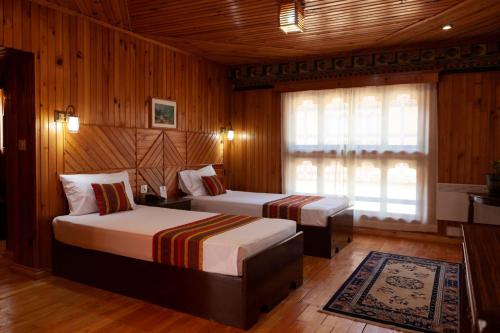 帕罗Hotel Olathang的配有木墙和木地板的客房中的两张床