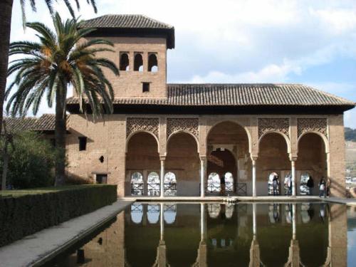 格拉纳达casa carmen alhambra的水体旁有棕榈树的建筑