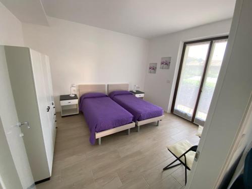 托尔博莱Casa Martinelli的一间卧室设有紫色的床和窗户