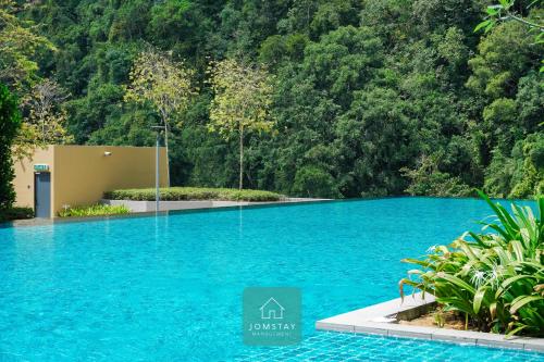 淡文JOMSTAY Sunway Onsen Suites Ipoh - Lost World of Tambun Ipoh Waterpark的森林前的蓝色海水游泳池