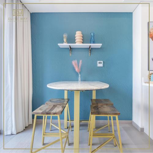 迪拜Impressive 3BR Villa-Akoya的一张桌子和两张凳子,位于一间蓝色墙壁的房间