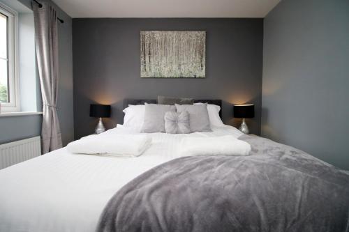 皇家伍顿巴西特Buxton Way by Tŷ SA - 3 bedroom house的一间卧室配有一张带两盏灯的大型白色床。