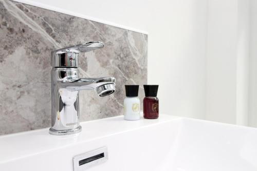 纽波特Modern 1 Bedroom - Caxton Place by Tŷ SA的浴室水槽配有水龙头和2瓶肥皂