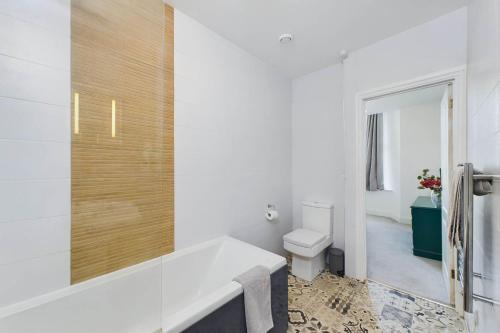 托基Loveliest Homes Torquay - 3 bed, 2 bathroom, balcony, parking的白色的浴室设有浴缸和卫生间。