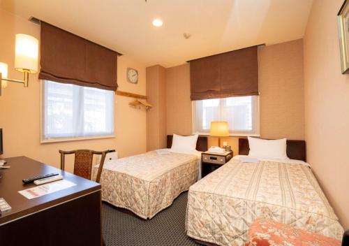 桐生市桐生爱斯酒店的酒店客房配有两张床和一张书桌