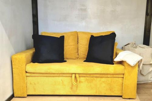 哥廷根City Apartment als Raumwunder的黄色柳条沙发,上面有两个黑色枕头