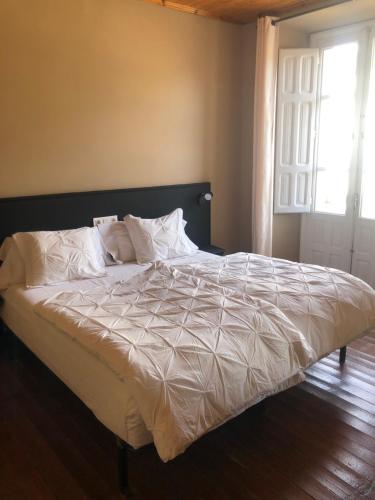 特里亚卡斯特拉Pension Casa Simon的卧室内的一张带白色床单和枕头的床