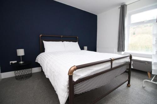 Quakers YardStation Terrace by Tŷ SA - 3 Bed in Mountain Ash的一间卧室设有一张蓝色墙壁的大床