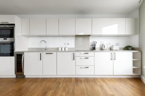 伦敦The Islington Collection的白色的厨房配有白色橱柜和木地板