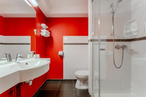 Beaurains阿斯阿拉斯包兰斯酒店的一间带红色墙壁、卫生间和水槽的浴室