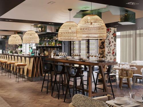 波尔多Novotel Bordeaux Centre Ville的餐厅设有带凳子的大型木制酒吧