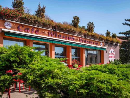 科尔马ibis Colmar Est - Hotel Restaurant en Alsace的一座橘色的建筑,上面有植物
