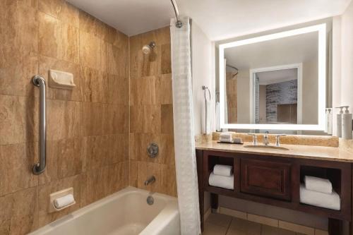 欧弗兰帕克Embassy Suites by Hilton Kansas City Overland Park的带浴缸、水槽和镜子的浴室
