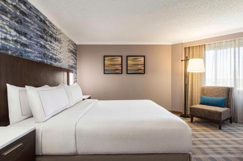 欧弗兰帕克Embassy Suites by Hilton Kansas City Overland Park的酒店客房带一张大床和一把椅子