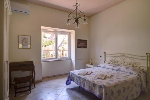 泰卡斯Casa Vacanze Il Gatto Rosso的一间卧室设有一张床、一个窗口和一张桌子