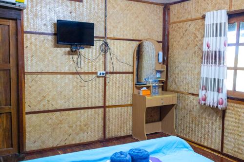 彭世洛Ruenpakkiangnan เรือนพักเคียงน่าน的客房设有一张带镜子的床和一台电视
