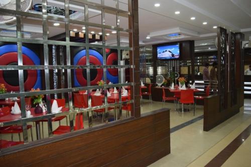 木尔坦Five Mounts Hotel And Restaurant的一间带红色椅子的餐厅和一间用餐室