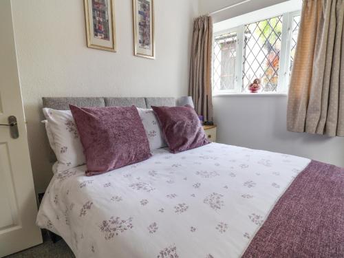 锡顿Sea Haven的一间卧室配有一张带紫色枕头的床和窗户。