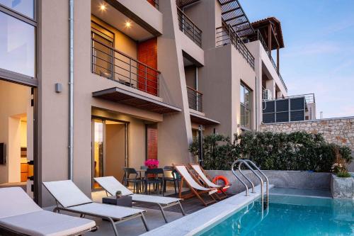 干尼亚Omnia Luxury Villas的房屋设有游泳池、椅子和桌子