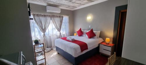 塔巴津比Tee Cee Marvelous Guesthouse的一间卧室配有一张带红色枕头的床和一扇窗户